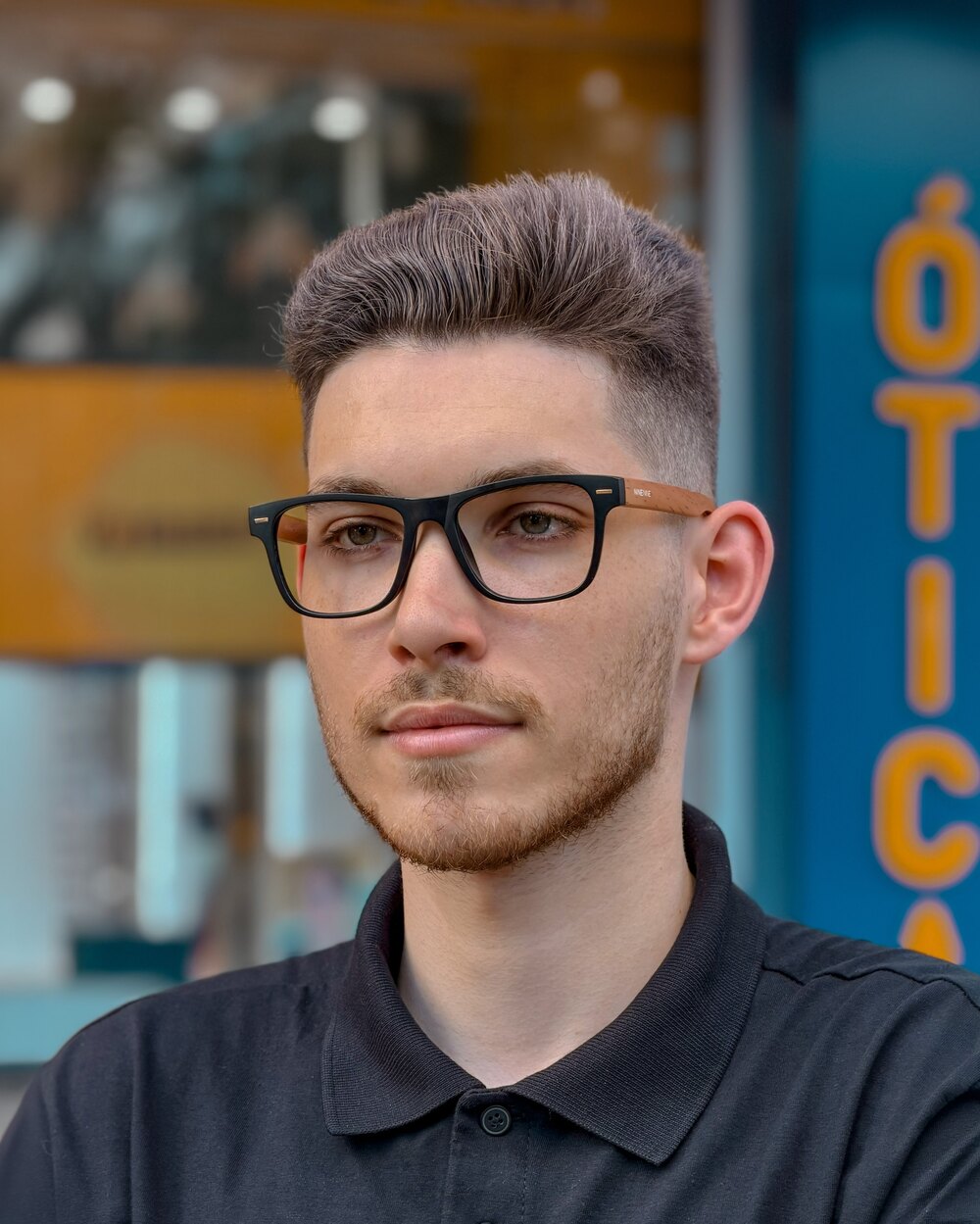 Homem usando armação de grau preta na frente da 99 Óticas